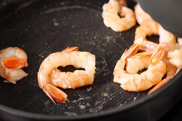 Креветки разморозить и очистить. В сковороду налить масло и обжарить креветки в течение 2 минут.
