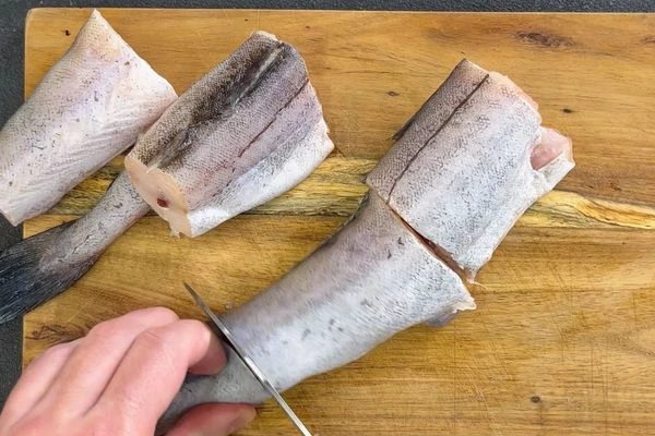 Минтай разморозить на нижней полке холодильника, удалить внутренности, промыть. Нарезать на порционные куски.