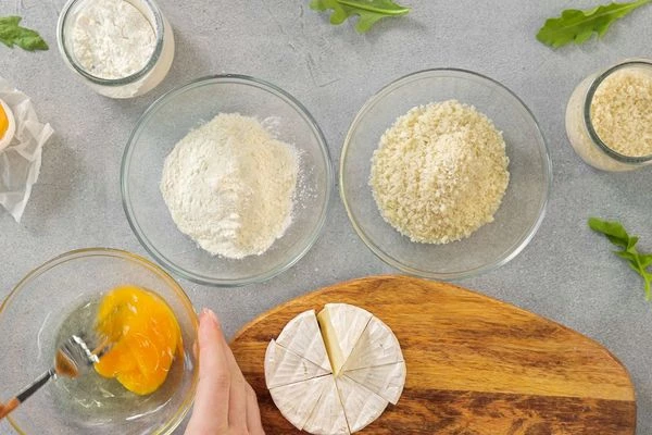 Камамбер нарезать на 8 частей.
Яйцо разбить в емкость, взбить вилкой. Муку и сухари насыпать в разные емкости.
