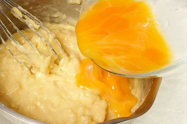 В остывшее тесто частями вбить яйцо, хорошо перемешивая венчиком до эластичной массы. Процедить через 2 слоя марли, чтобы не было комочков.