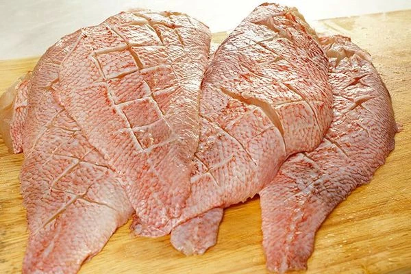 Сделать надрезы на коже окуня в виде "решеточки". Сбрызнуть рыбу лимонным соком, посолить, поперчить по вкусу.