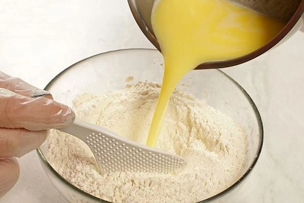 Влить получившуюся смесь в муку и замесить тесто.