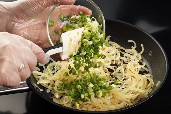 На разогретой с растительным маслом сковороде обжарить нарезанный соломкой репчатый лук до золотистого цвета. Снять с огня. Затем добавить мелко нарезанный зеленый лук.