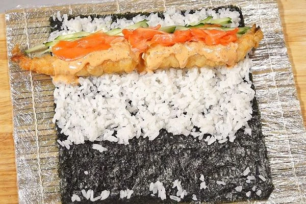 Полить креветки острым соусом, накрыть лепестками маринованного имбиря.