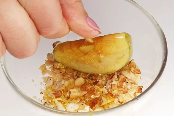 Затем яблоки в карамели опустить в рубленные орехи или кокосовую стружку. Переложить на пергаментный лист.