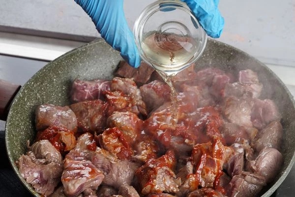 На разогретой с растительным маслом сковороде обжарить мясо 3-4 минуты, добавить томатную пасту, винный уксус и воду.