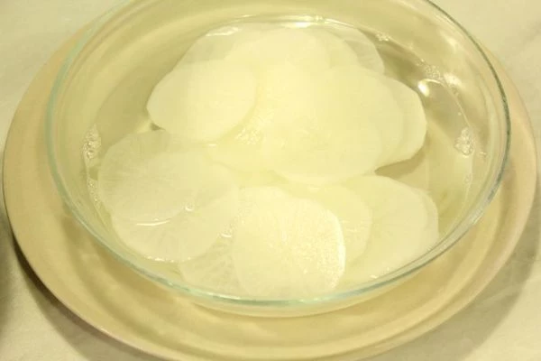 Корень дайкона очистить с помощью овощечистки, промыть, нарезать тонкими кружочками.