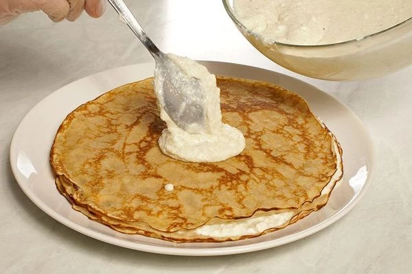 Затем закрыть еще одним блином, смазать кремом. Чередовать так крем-блин, пока блины не закончатся. Верхним слоем должен лежать блин. Накрыть пищевой пленкой и дать постоять в холодильнике 1-2 часа.