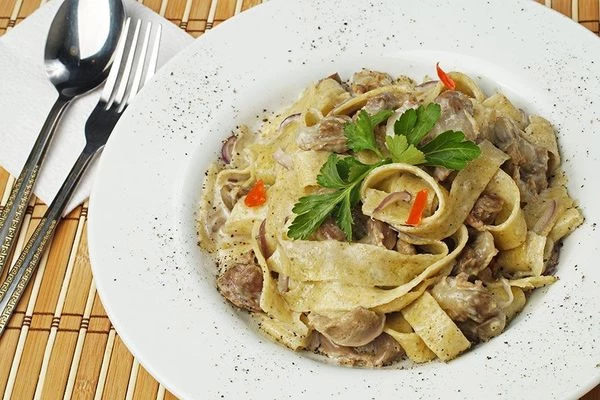 Готовую пасту выложить в тарелку, украсить зеленью и молотым перцем.