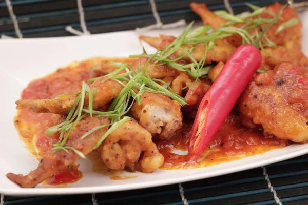 Выложить готовые крылья с соусом на тарелку, украсить тонкими перышками зеленого лука.