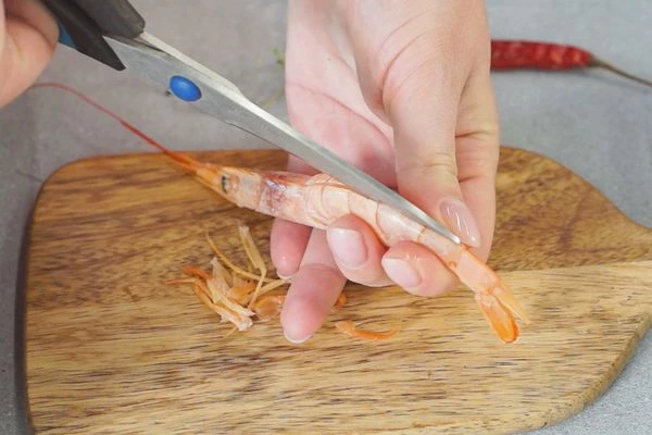 Креветки разморозить на нижней полке холодильника, промыть. Обрезать лапки. С помощью ножниц сделать надрез от головы к хвосту по спинке, удалить кишечник. 