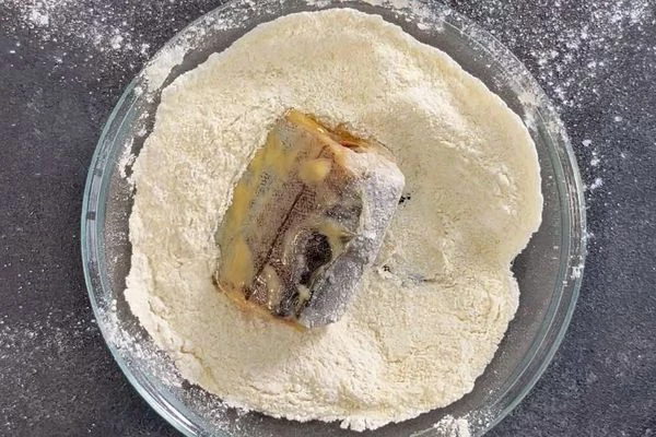 Запанировать кусочки минтая в смеси муки и манной крупы.