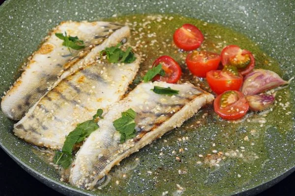 Добавить половинки помидоров черри и листики мяты. Обжаривать 1 минуту, снять с огня. 