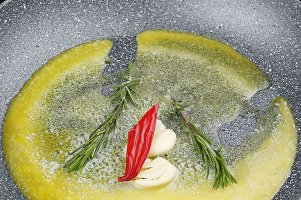 На сковороде разогреть сливочное и растительное масло, добавить раздавленный чеснок, перец чили, розмарин. 