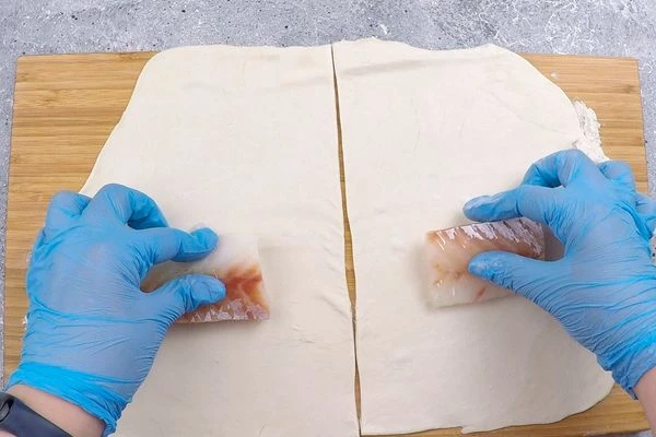 Треску разморозить естественным способом на нижней полке холодильника, разрезать на порции.  Выложить по центру теста.