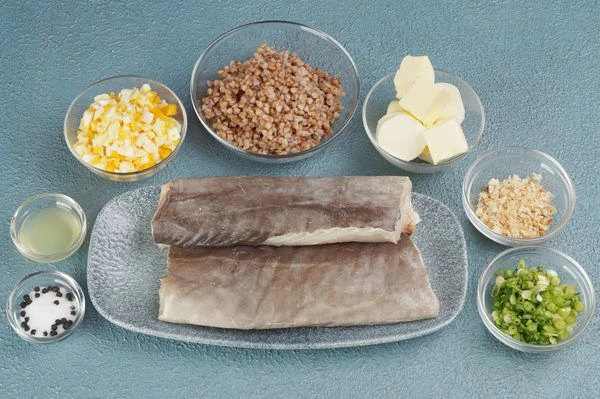 Мольву разморозить естественным способом на нижней полке холодильника. Разрезать вдоль хребта на 2 филе. Яйца куриные отварить, нарезать мелким кубиком, зеленый лук мелко порезать, отварить гречку.