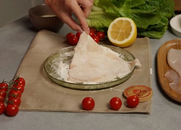 Кальмара разморозить на нижней полке холодильника, очистить, удалить плавники. Тушку разрезать вдоль с одной стороны. Посолить и поперчить, обвалять в муке.