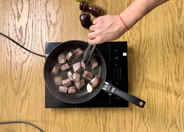 Мясо обжарить на сильном огне с добавлением тимьяна и дольки чеснока, в течение 2-3 минут.