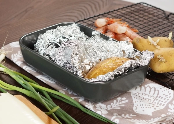 Достать из духовки, развернуть фольгу, на каждом картофель сделать продольный надрез. Вилкой размять картофель внутри, посолить и поперчить, добавить сливочное масло. 