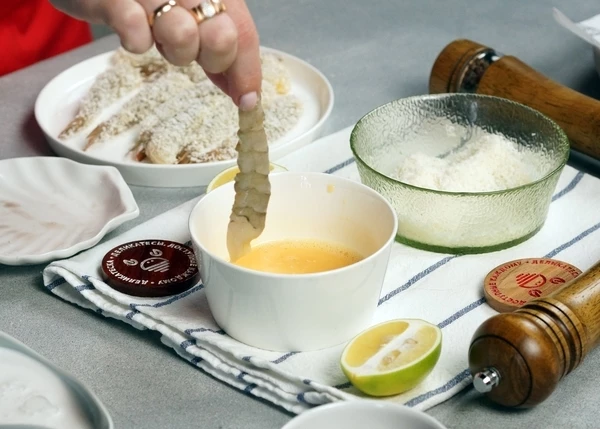 Креветки разморозить на нижней полке холодильника. Посолить. Обмакнуть во взбитое яйцо. 