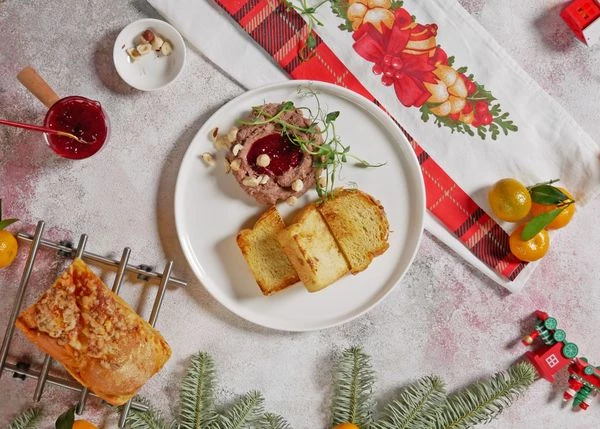 На тарелку для подачи выложить паштет, протертую клюкву, обжаренные на сухой сковороде ломтики хлеба. Оформить фундуком и микрозеленью. Приятного аппетита!
