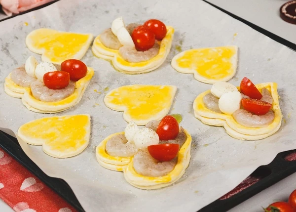 В центр теста разложить креветки, половинки черри и сыр, посолить и поперчить. Выпекать в разогретой до 180 градусов духовке в течение 10-11 минут.
