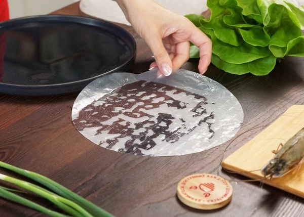 Рисовую бумагу намочить в воде. Выложить на стол. 