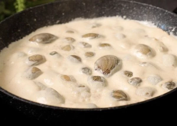 Затем в сковороду выложить вонголе и на небольшом огне прогреть в течение 5 минут. Чтобы все моллюски открылись и напитались соусом. 