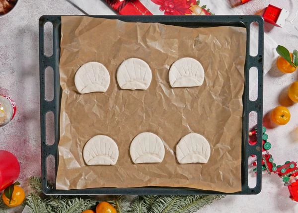 Тесто разморозить на нижней полке холодильника. Слегка раскатать, вырезать кружочки, верхнюю часть загнуть. Ножом сделать насечки. 