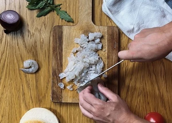 Для приготовления бургера необходимо разморозить креветки на нижней полке холодильника, промыть, обсушить бумажным полотенцем и мелко нарезать (можно использовать блендер или мясорубку).