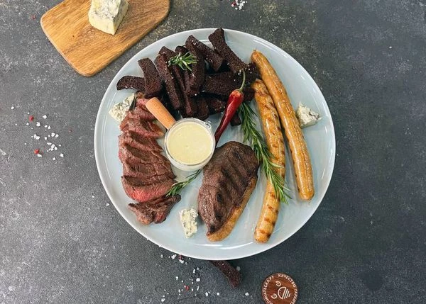 На тарелку для подачи выложить колбаски, стейки, гренки. Рядом выложить кусочки сыра. Оформить розмарином. Подавать с соусом. Приятного аппетита!
