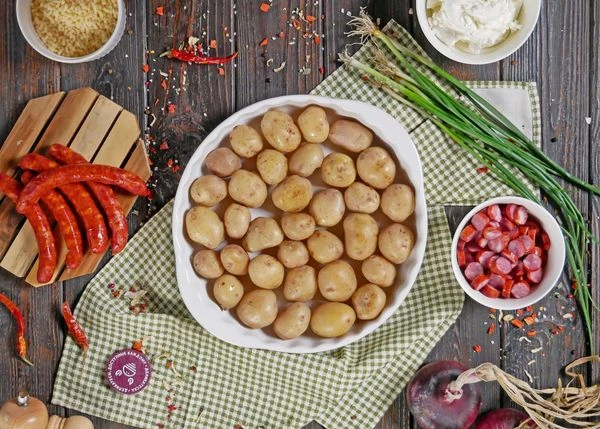 Картофель вымыть, отварить. Выложить в форму для запекания.