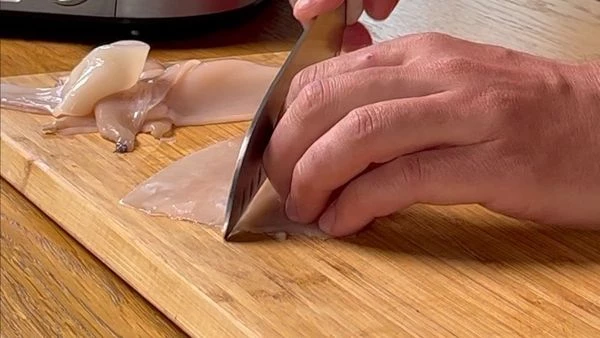 Кальмары разморозить на нижней полке холодильника, промыть под проточной водой. Удалить внутренности, потянув за щупальца. Снять тонкую шкурку и убрать хитиновую пластину. Щупальца отделить от основной части головы. Очистить от клюва. 