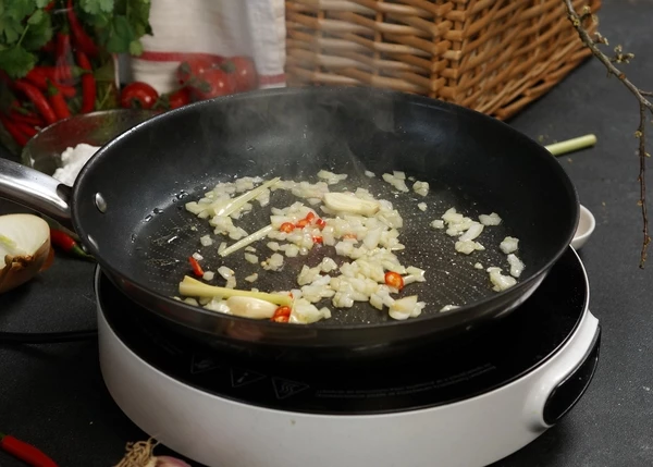 В сковороду налить масло, обжарить нарезанный лук, чеснок, перец и лемонграсс. 