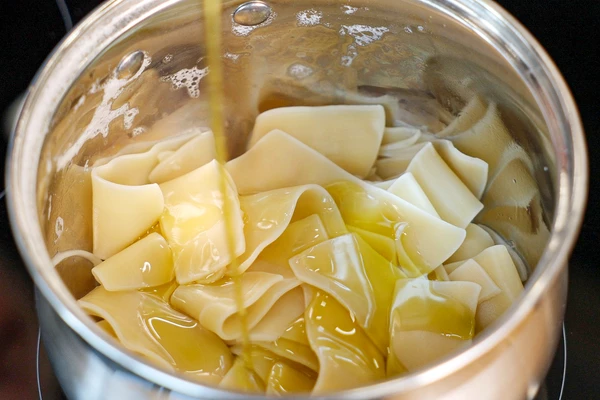 Отварить пасту в соответствии с инструкцией на упаковке. У нас феттучине из твердых сортов — до состояния аль-денте их необходимо варить 10 минут в большом количестве подсоленной воды. Затем слить воду и заправить небольшим количеством оливкового масла, чтобы паста не слиплась.