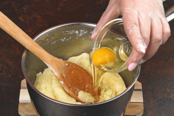  Немного остудить, затем по 1 шт добавлять яйца, так же интенсивно перемешивая деревянной лопаткой до однородного состояния.