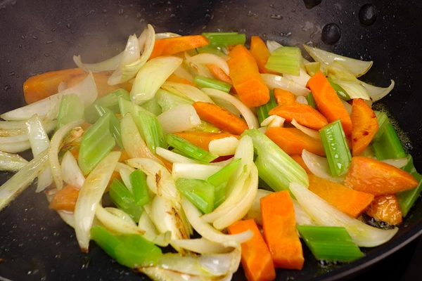 На хорошо разогретой с растительным маслом сковороде обжарить сначала лук и морковь до золотистого цвета, затем добавить сельдерей и чеснок.