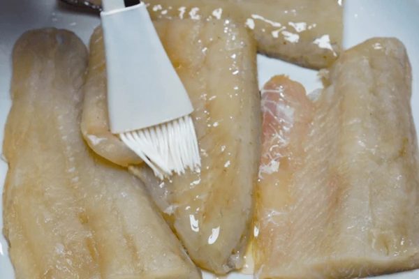 Филе судака разморозить естественным способом на нижней полке холодильника, обсушить бумажным полотенцем. Проверить на наличие крупных костей, удалить их пинцетом, если есть необходимость. Разрезать на порционные кусочки, сбрызнуть растительным маслом.