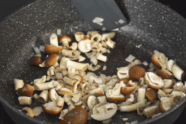В этой же сковороде обжарить лук и чеснок. Добавить опята, жарить 3 – 4 минуты. 
