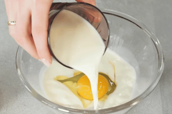 В емкость разбить яйцо, добавить молоко, соль, перец, перемешать венчиком. 