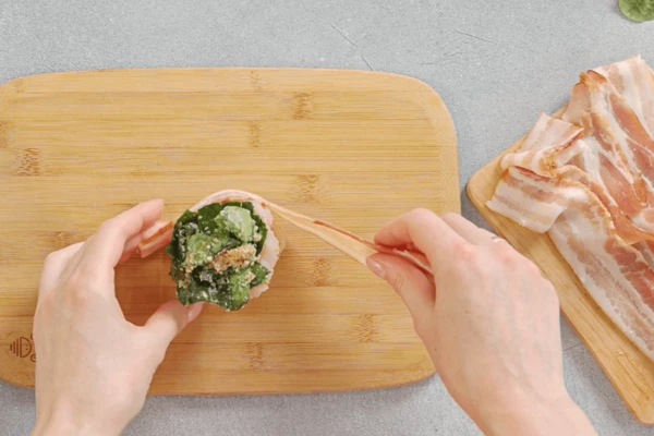 Затем рулетики обернуть полоской бекона и скрепить шпажкой.