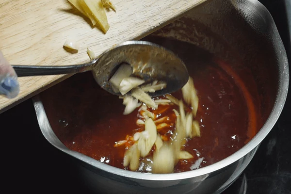 Чеснок и имбирь нарезать тонкими пластиками, добавить в соус и снять с огня.