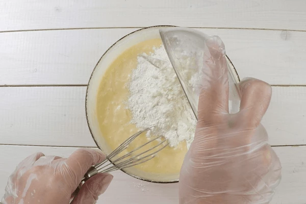  Хорошо перемешать, затем добавить порциями муку.