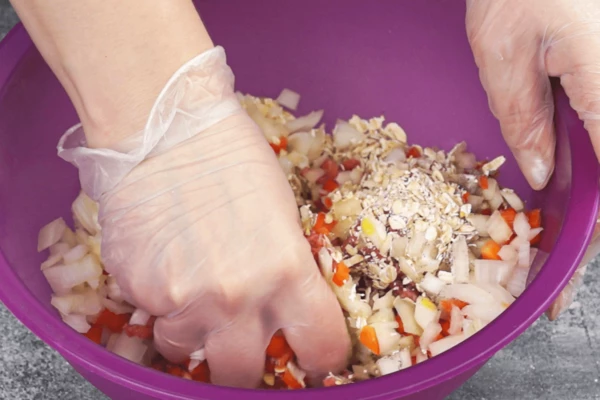  В глубокой чашке смешать фарш, нарезанные овощи, яйца, соль, перец, хлопья, помидоры в собственном соку (если помидоры целые, то можно разрезать на 2-3 части), хорошо вымешать до однородной консистенции. 