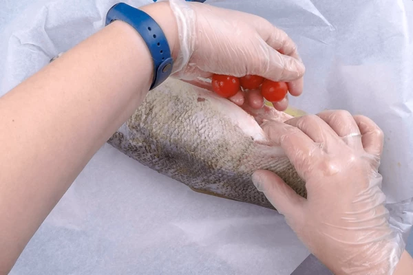 Посолить, поперчить.  В брюшко заправить несколько веточек зелени, раздавленные зубчики чеснока и помидоры черри. 