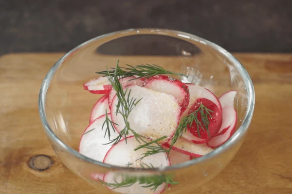 Редис нарезать слайсами, замариновать с укропом, солью, сахаром, молотым перцем, соком лимона и сушеным чесноком.