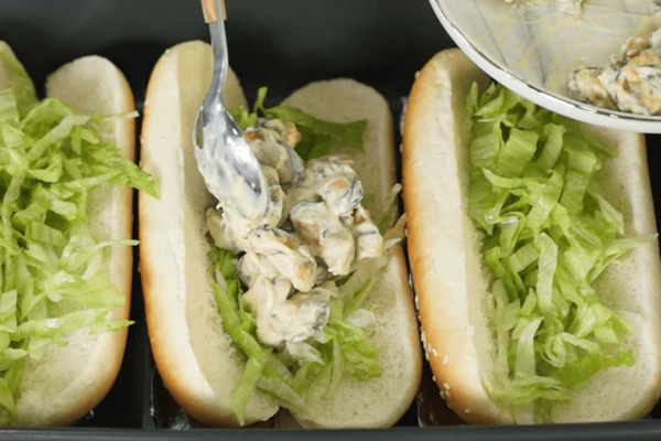 Булочки разморозить на нижней полке холодильника.
Айсберг вымыть, обсушить, нарезать тонкой соломкой.
На булочку для хот-дога выложить нарезанный айсберг, мидии с вешенками.