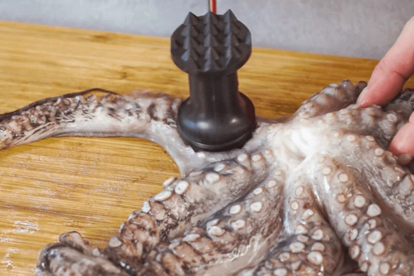 Осьминога разморозить на нижней полке холодильника, промыть. Отбить кухонным молотком.