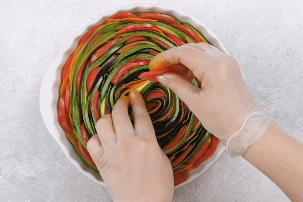  В форму выложить по спирали нарезанные овощи (баклажан, морковь, цукини). Затем между рядами вставить кружки помидора.