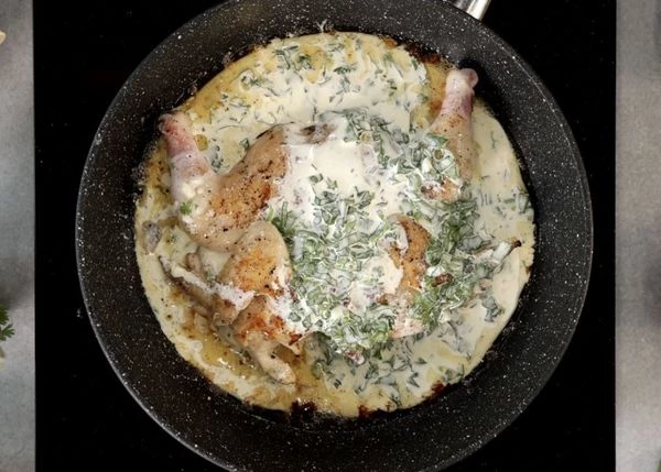 Залить в сковороду к цыпленку, добавить кусочки сыра, накрыть крышкой и томить на медленном огне 10 минут, периодически переворачивая.